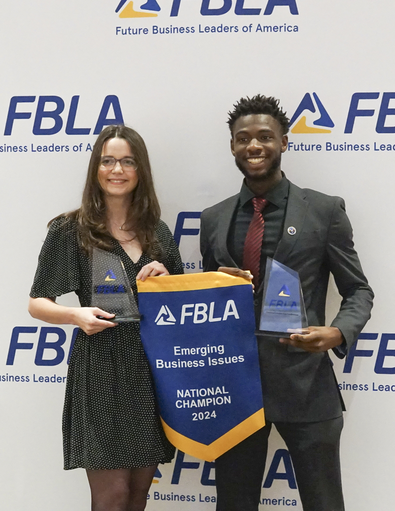 Two students display a Emerging Business Issues Banner at the 2024 FBLA National Competition.